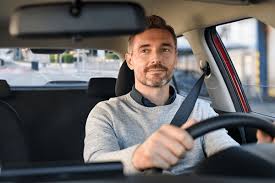 [A confident driver sitting in their car, smiling after finding great auto insurance coverage through this site]